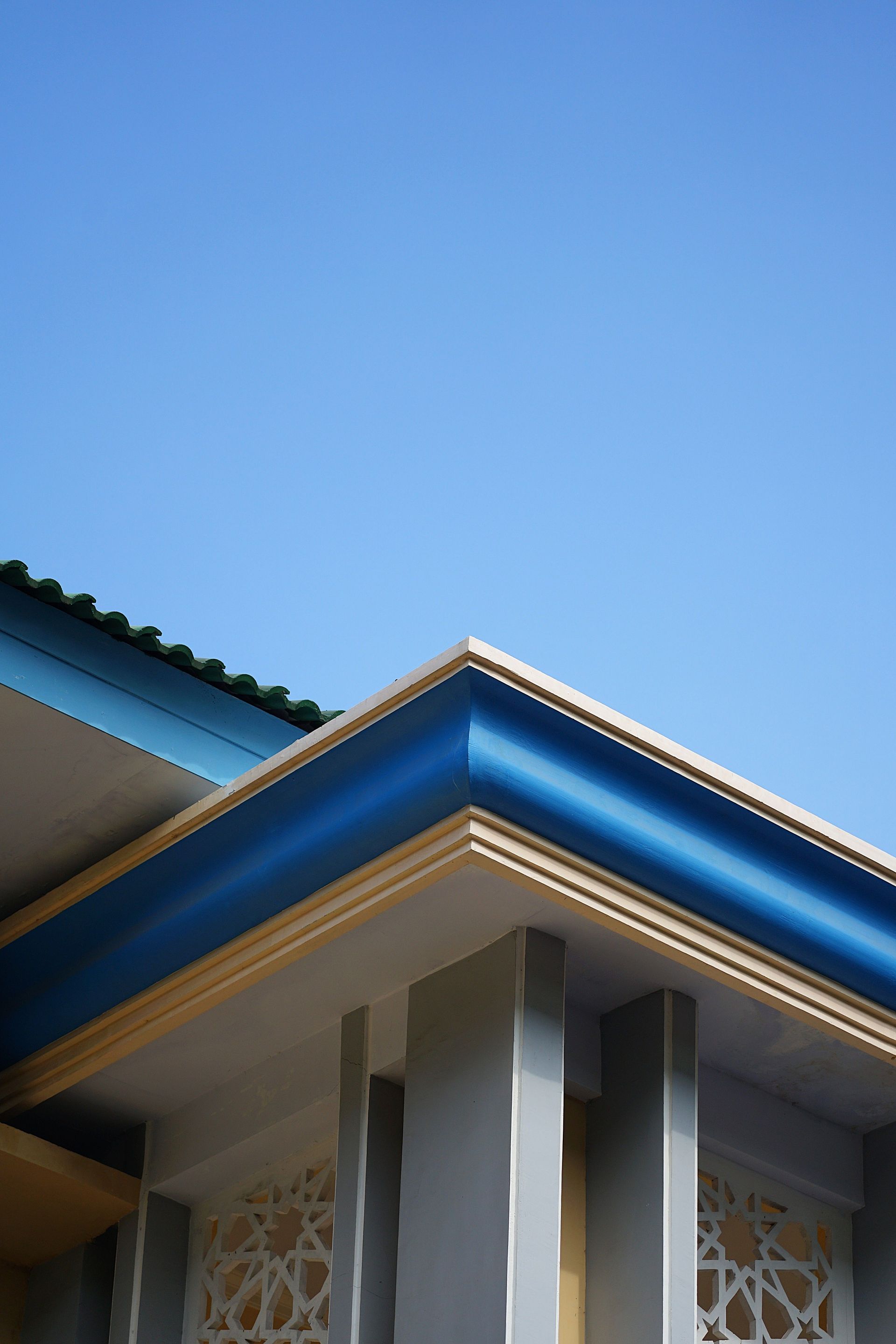 A clean, geometric view of a mosque's architectural detail in East Java under a blue sky.