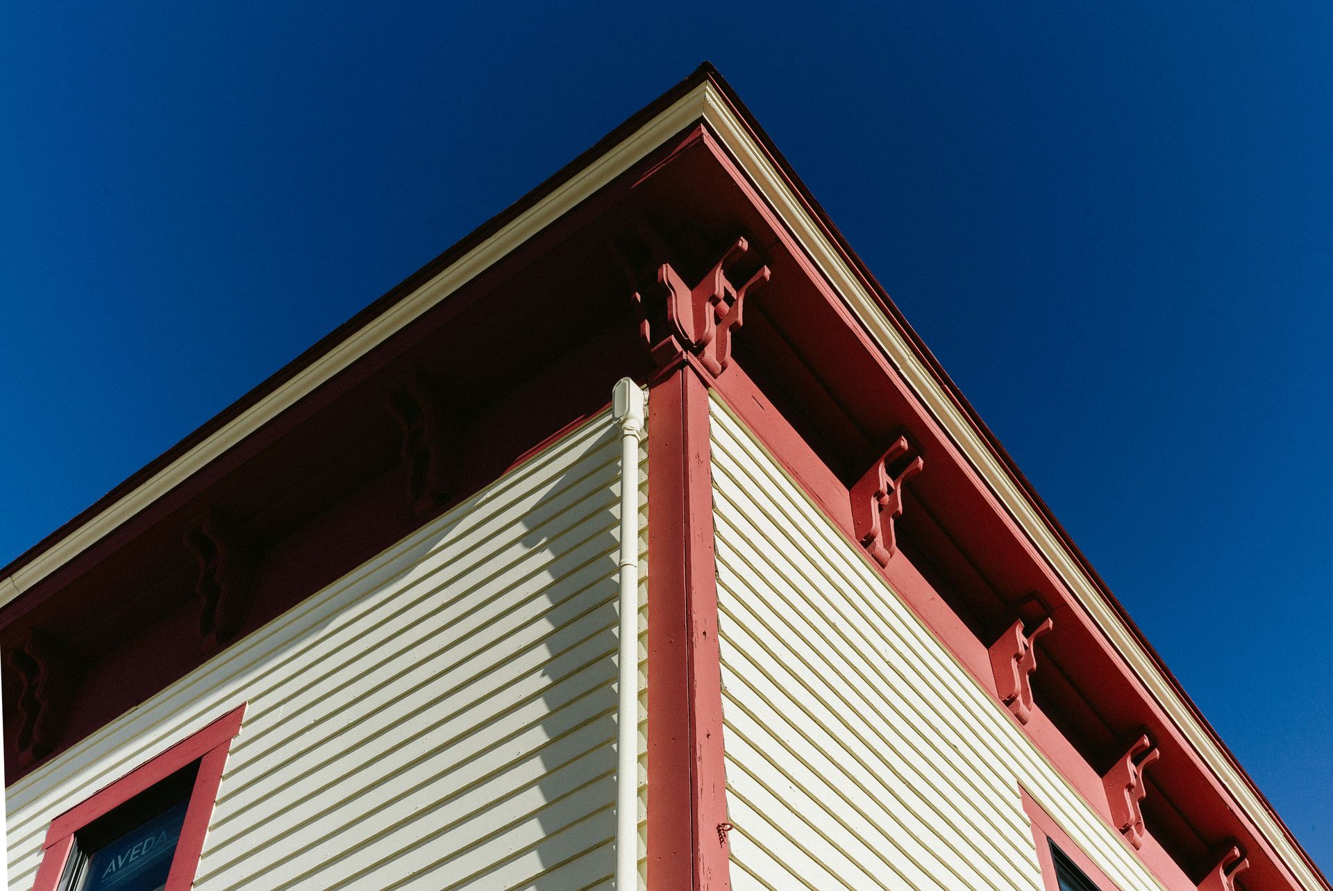 Corner of a house with white siding and red trim.